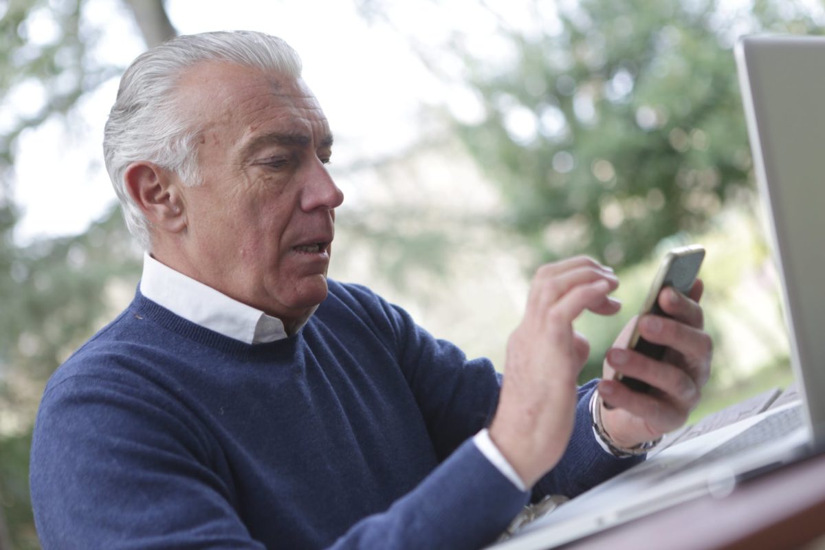 man in blue sweater holding smartphone